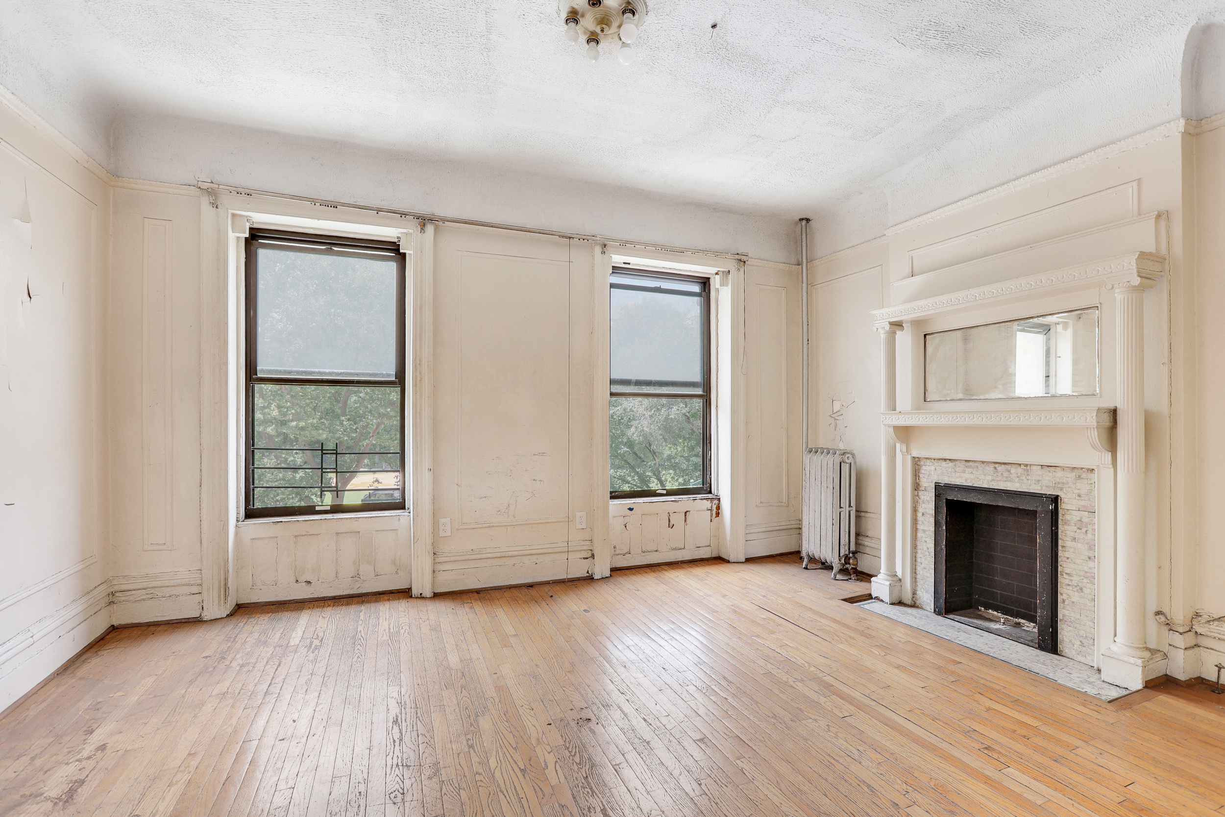 282 Manhattan Avenue, Unit 3N Manhattan, NY 10026 - Photo 2 of 17 an empty room with wooden floor fireplace and windows