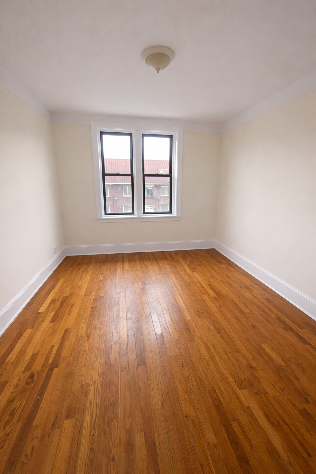 28-23 42nd Street, Unit D5 Queens, NY 11103 - Photo 9 of 10 a view of an empty room with wooden floor and a window