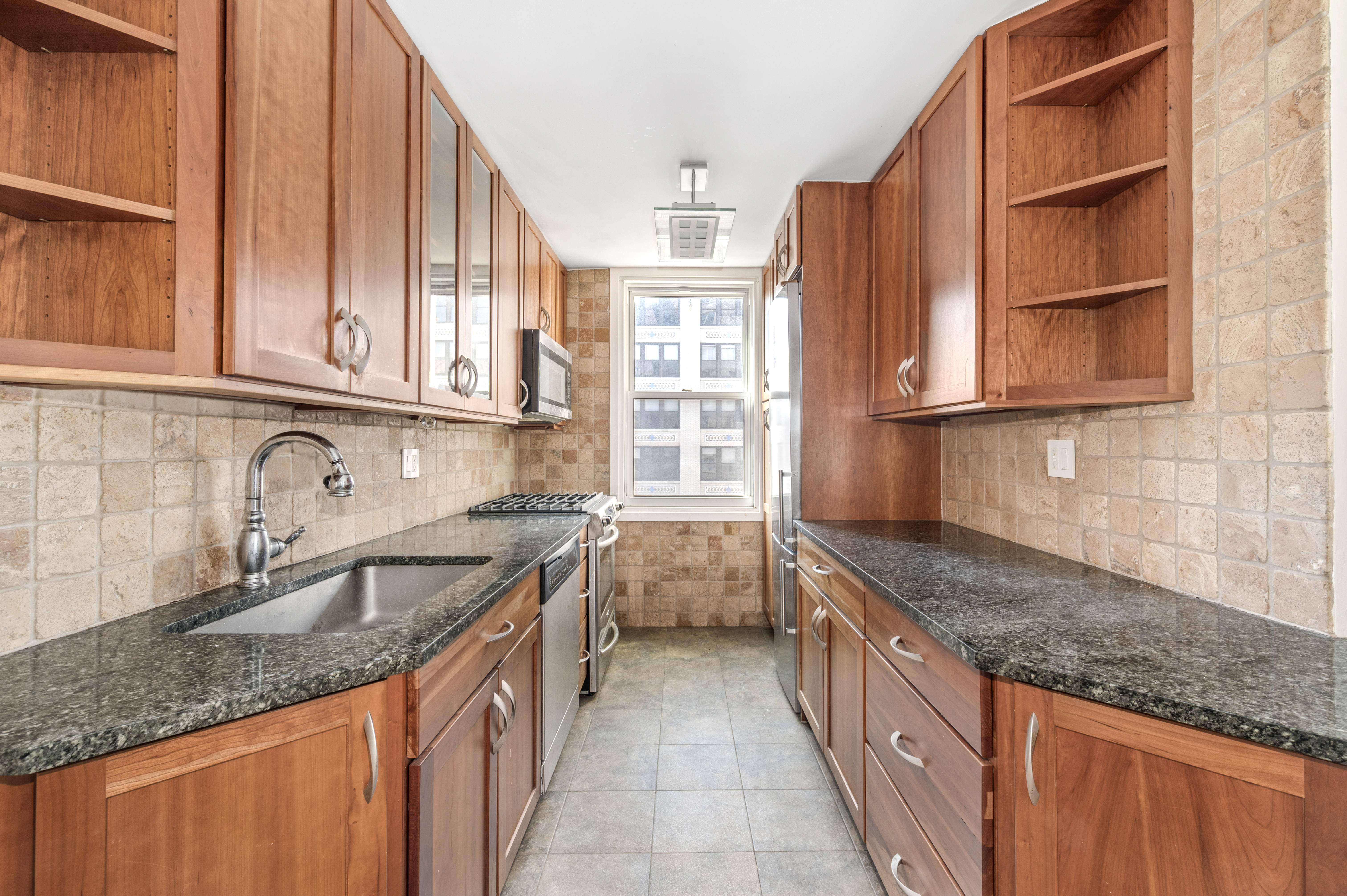 77 7th Avenue, Unit 10N Manhattan, NY 10011 - Photo 5 of 13 a kitchen with stainless steel appliances granite countertop a sink and a stove