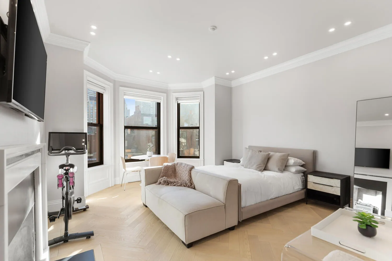 a spacious bedroom with a bed window table and television