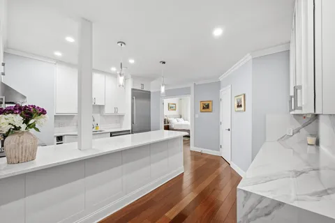 a large white kitchen with large window and stainless steel appliances