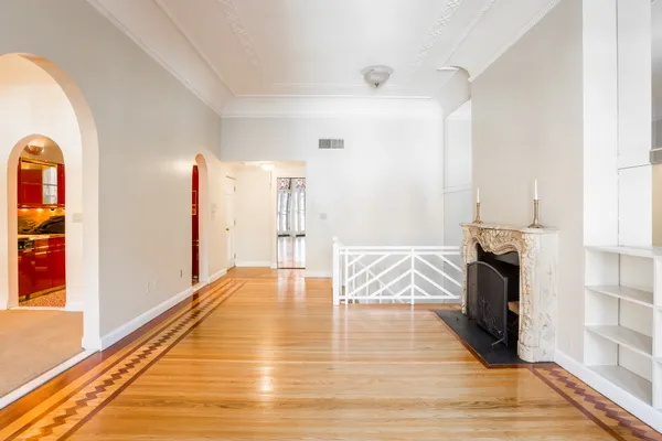 a view of empty room with wooden floor and fan