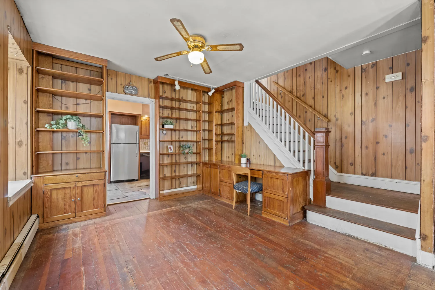 a view of empty room with wooden floor and fan