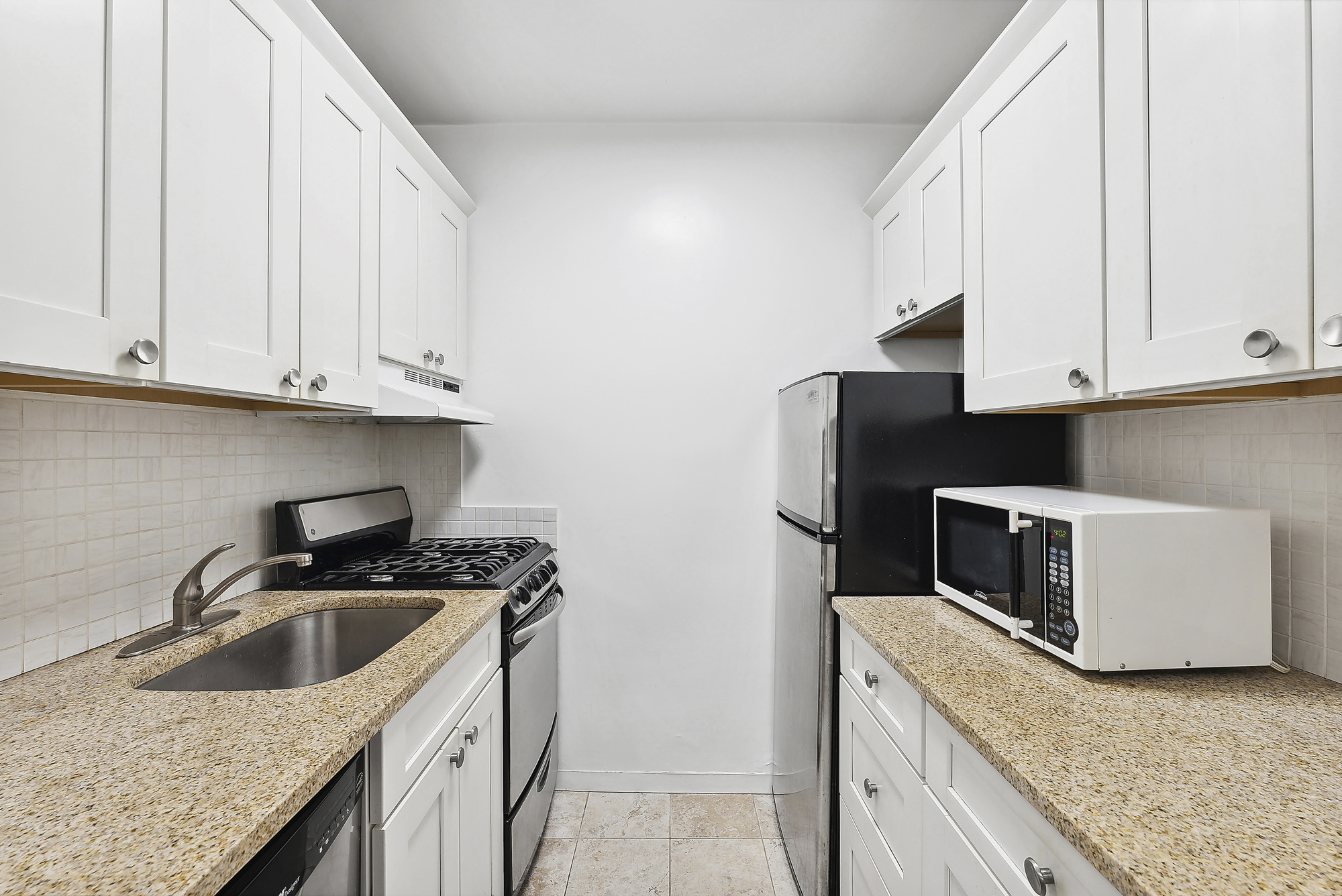 2 5th Avenue, Unit 2U Manhattan, NY 10011 - Photo 3 of 13 a kitchen with granite countertop white cabinets and stainless steel appliances