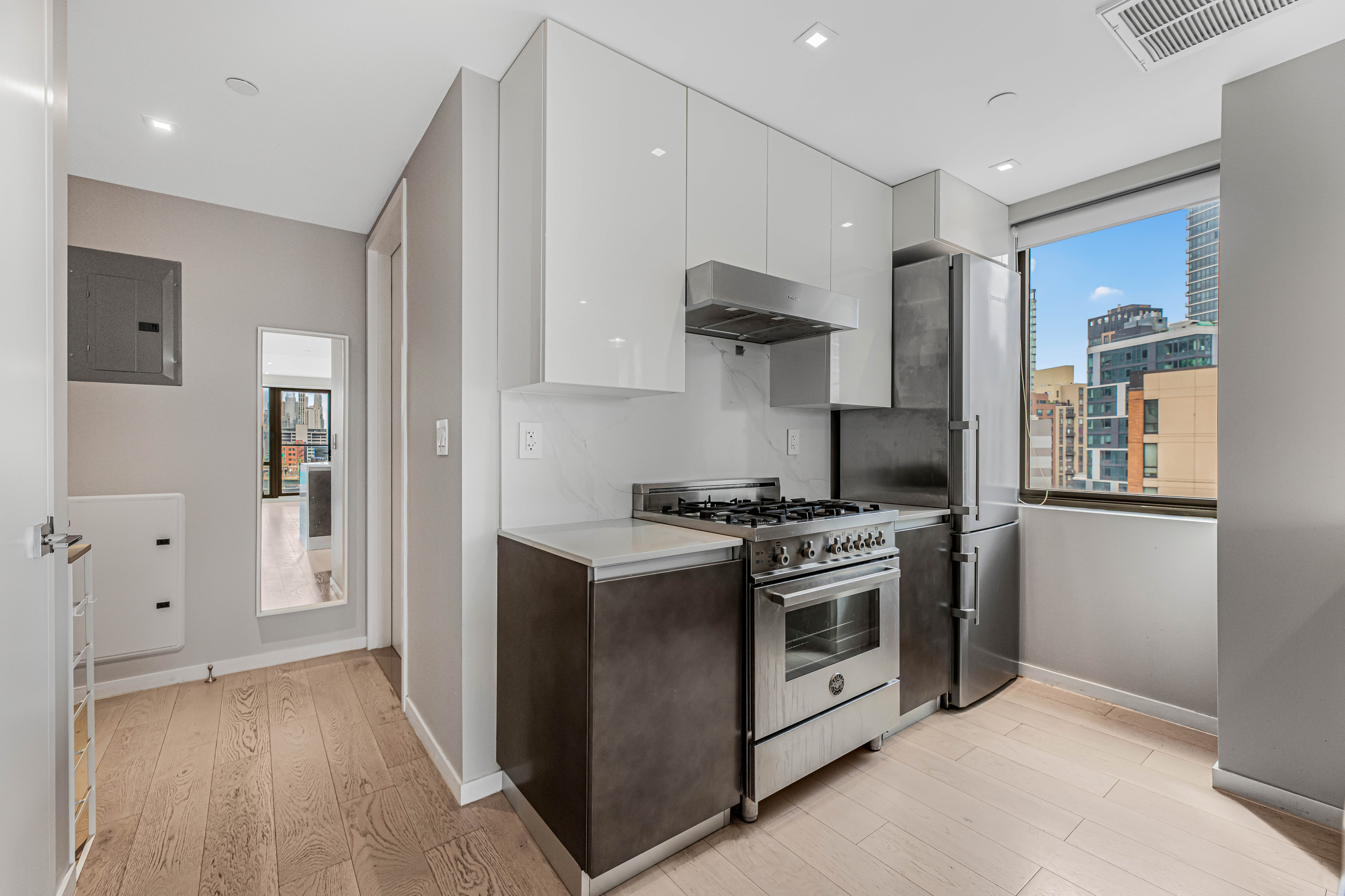 42-50 27th Street, Unit 9C Queens, NY 11101 - Photo 13 of 32 a kitchen with stainless steel appliances a stove a sink and a refrigerator