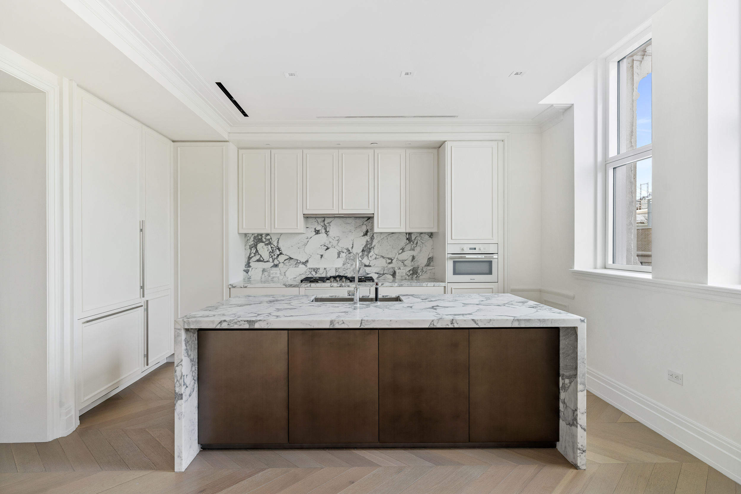 108 Leonard Street, Unit 12F Manhattan, NY 10013 - Photo 3 of 15 a kitchen with kitchen island granite countertop a sink window and cabinets