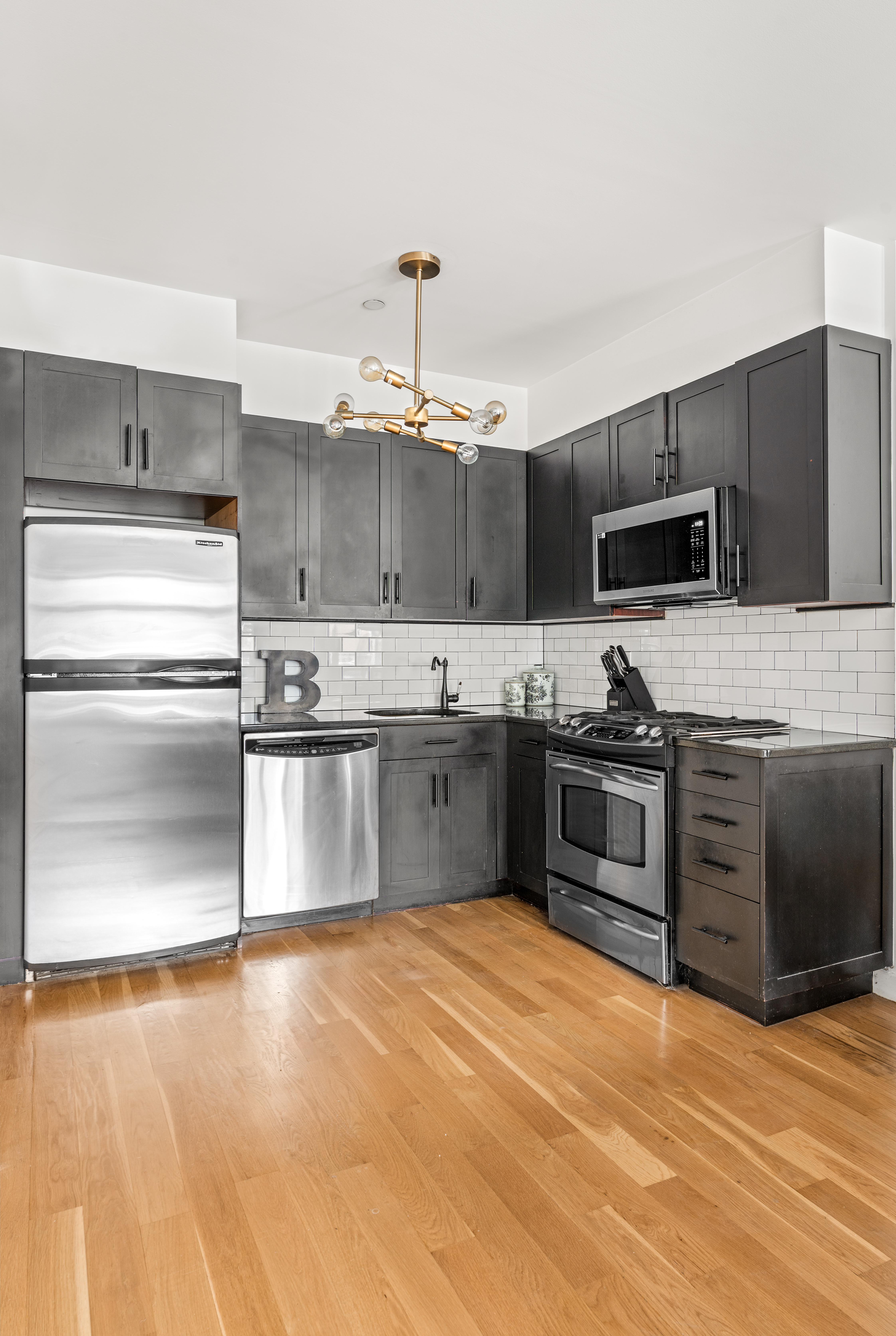 319 Humboldt Street, Unit 1A Brooklyn, NY 11211 - Photo 5 of 10 a kitchen with stainless steel appliances kitchen island granite countertop a stove top oven and cabinets