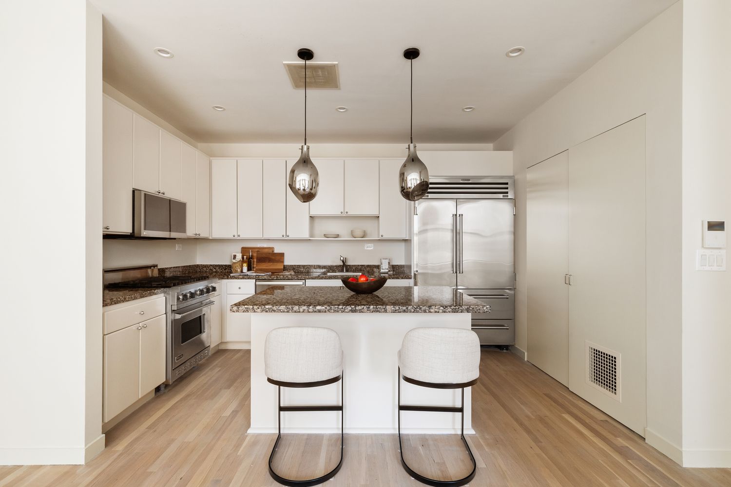 a kitchen with stainless steel appliances granite countertop a sink a stove and chairs