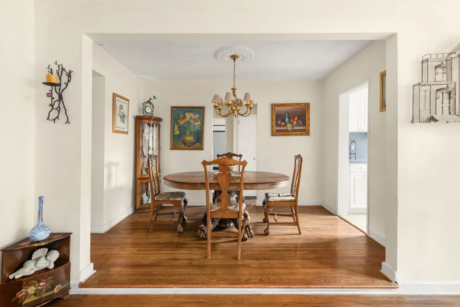 a dining room with wooden floor a chandelier a wooden table and chairs