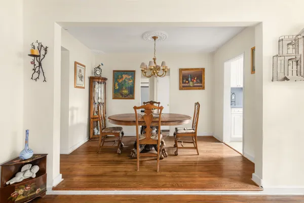 a dining room with wooden floor a chandelier a wooden table and chairs