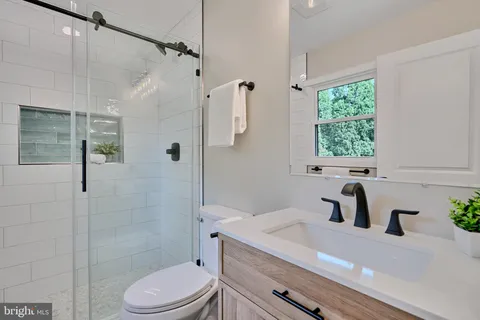 a bathroom with a sink a toilet a window and shower