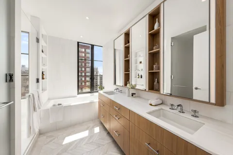 a bathroom with a double vanity sink a mirror a bathtub and next to a window