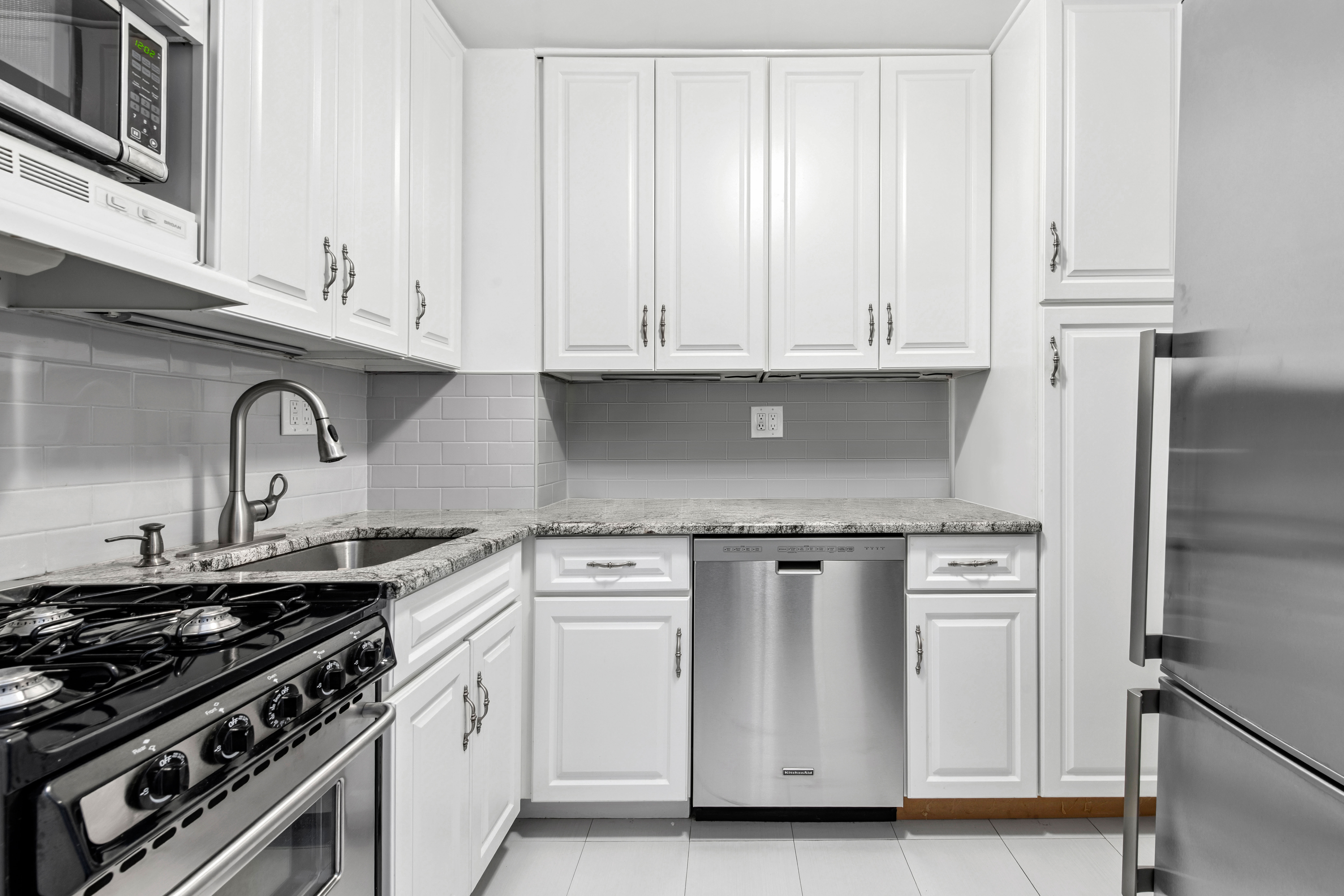 363 East 76th Street, Unit 6E Manhattan, NY 10021 - Photo 6 of 15 a kitchen with white cabinets and appliances