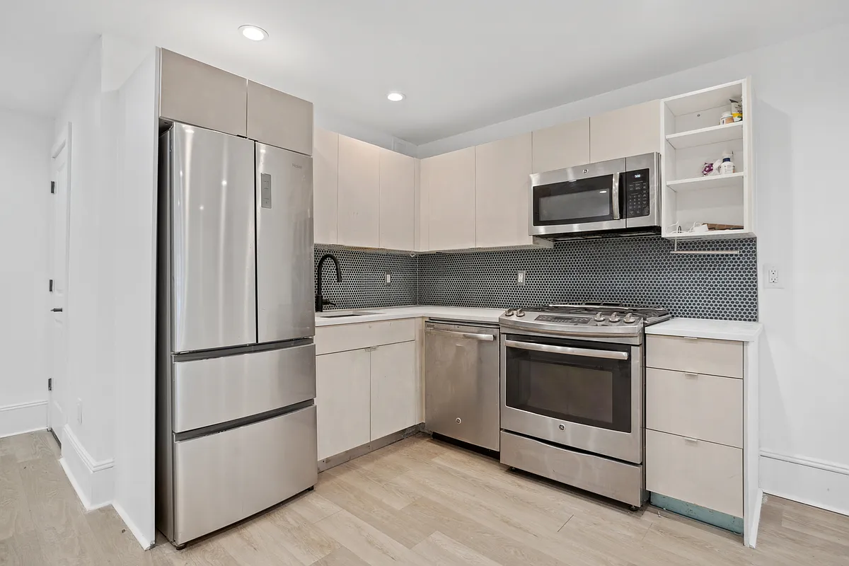 1316 Jefferson Avenue, Unit GDN Brooklyn, NY 11221 - Photo 2 of 6 a kitchen with stainless steel appliances granite countertop white cabinets a microwave a refrigerator and white cabinets