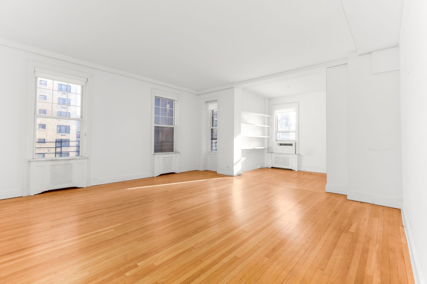 a view of an empty room with wooden floor and a window