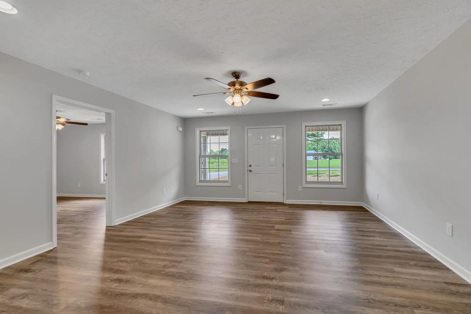 a view of an empty room with a window and wooden floor