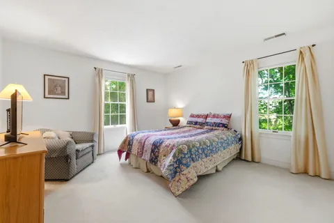 a bedroom with a bed table chair and a window