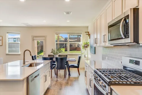 a kitchen with stainless steel appliances a kitchen island a stove a table and chairs