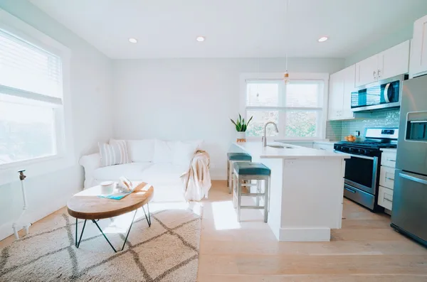 a kitchen with stainless steel appliances kitchen island granite countertop a dining table chairs and a refrigerator