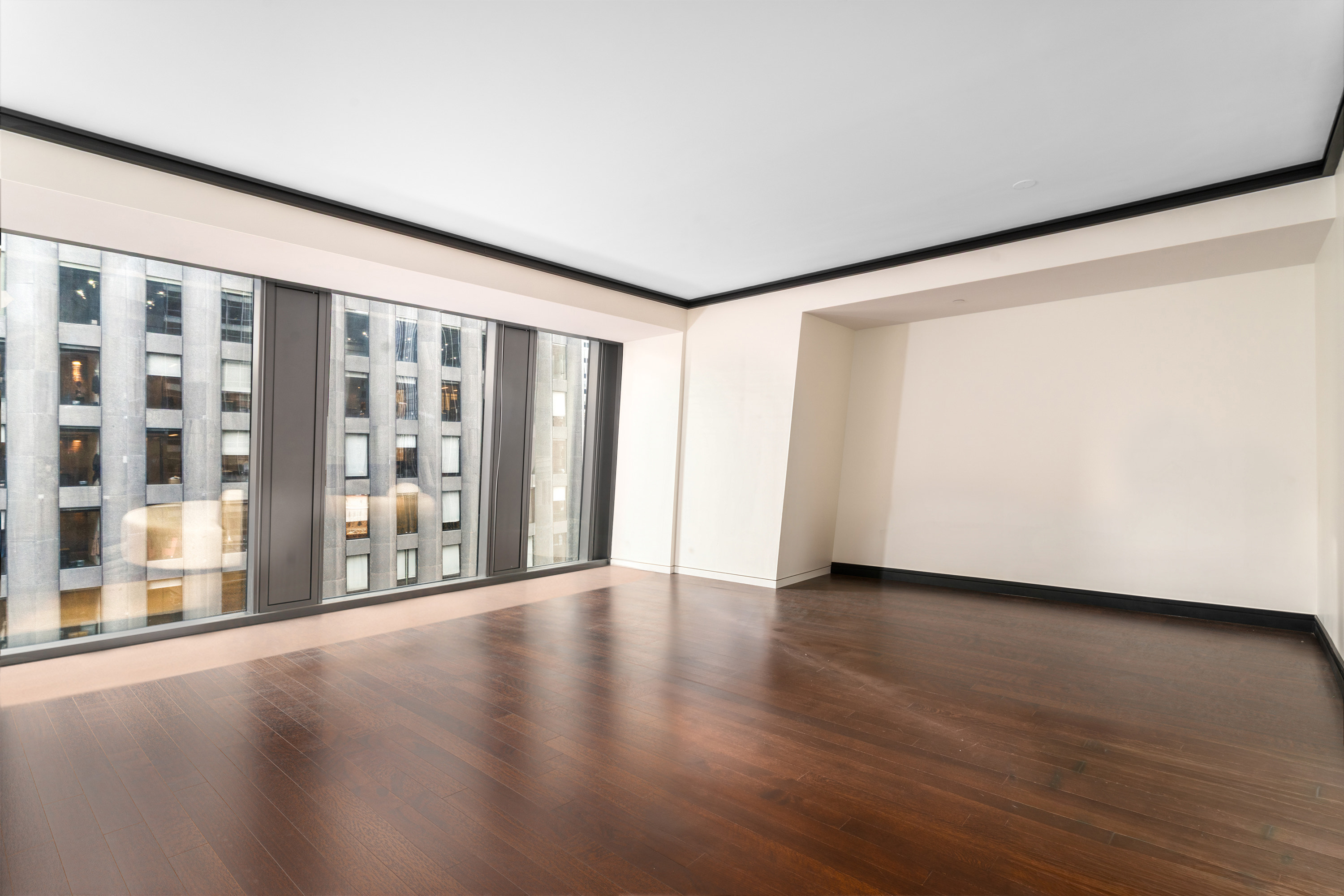 53 West 53rd Street, Unit 20E Manhattan, NY 10019 - Photo 4 of 11 a view of an empty room with wooden floor and a window