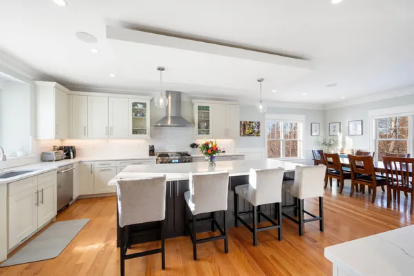 a kitchen with a dining table chairs cabinets wooden floor and appliances
