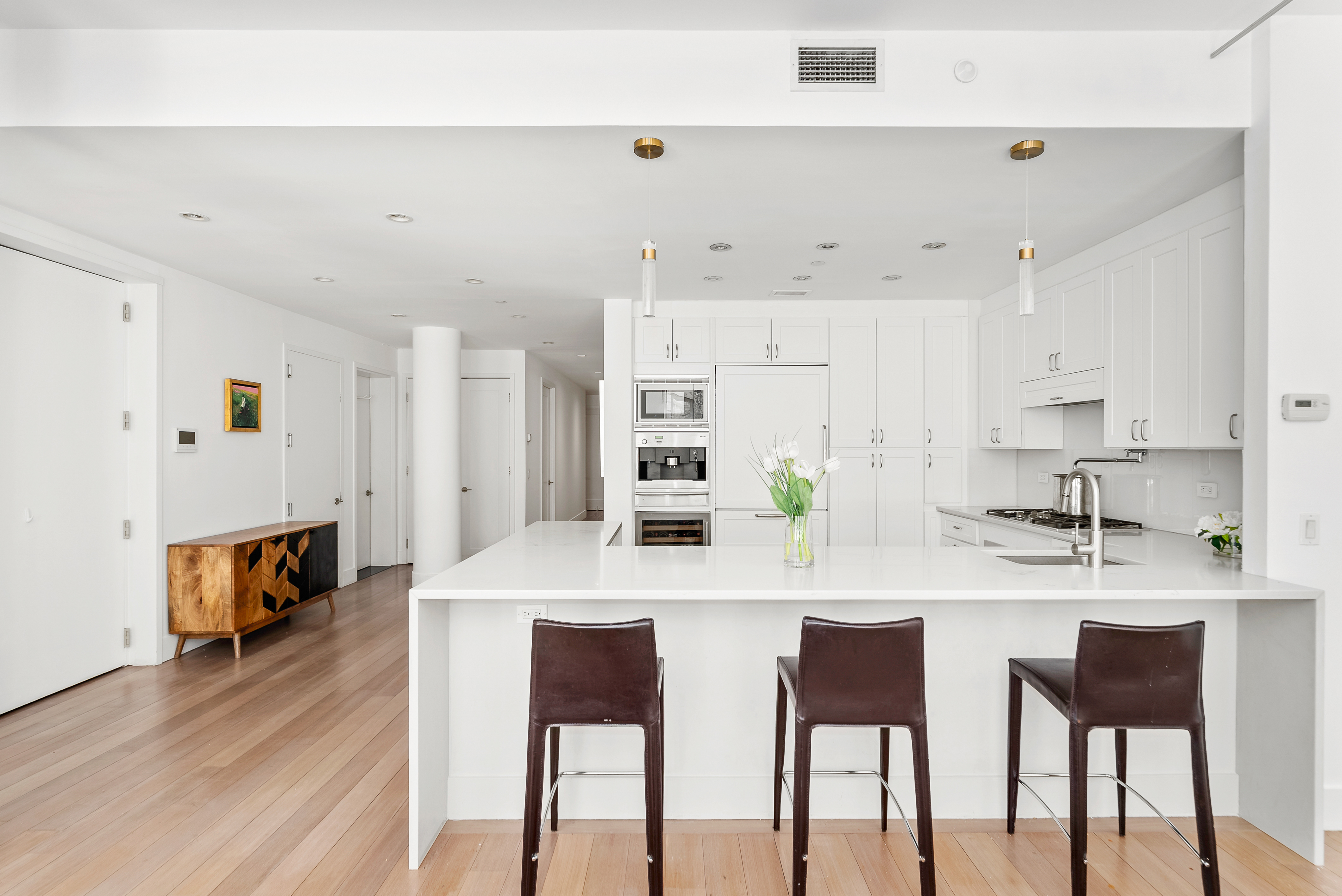 15 West 20th Street, Unit 9A Manhattan, NY 10011 - Photo 6 of 21 a kitchen with stainless steel appliances kitchen island granite countertop a dining table chairs and white cabinets