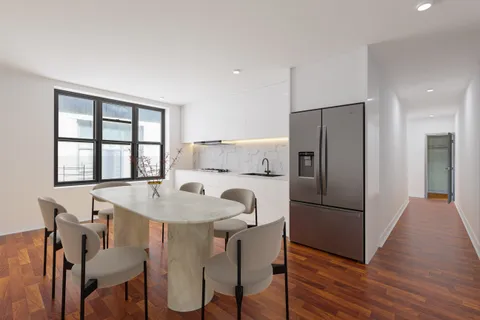 a kitchen with stainless steel appliances a refrigerator a table and chairs