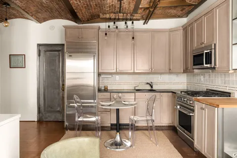 a kitchen with stainless steel appliances granite countertop a refrigerator a stove and white cabinets with wooden floor