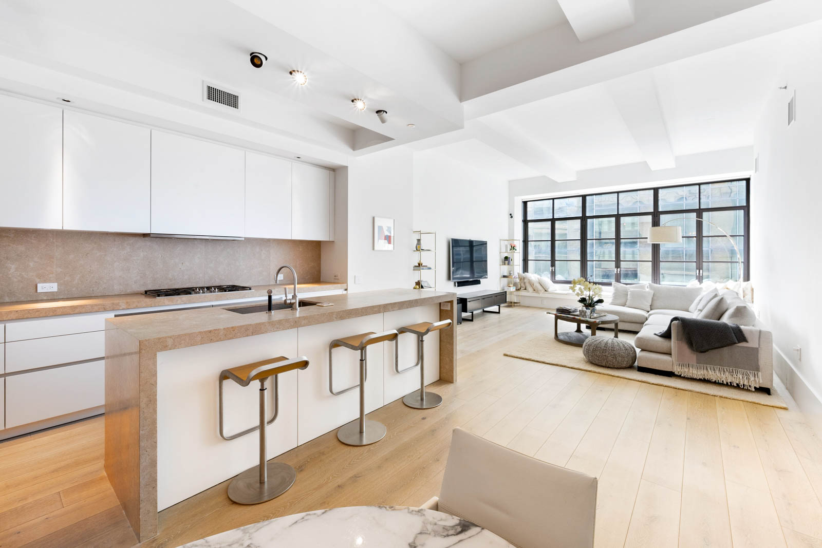 404 Park Avenue South, Unit 12D Manhattan, NY 10016 - Photo 1 of 1 a large white kitchen with stainless steel appliances granite countertop a lot of counter space and a couch