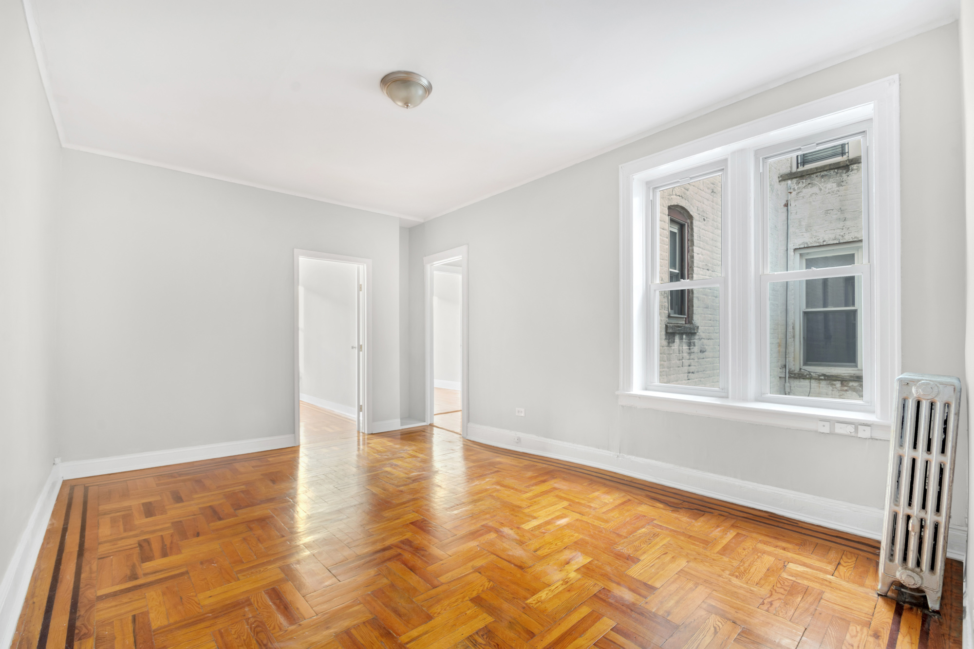 6811 Owls Head Court, Unit 2A Brooklyn, NY 11220 - Photo 2 of 5 a view of an empty room with wooden floor and a window
