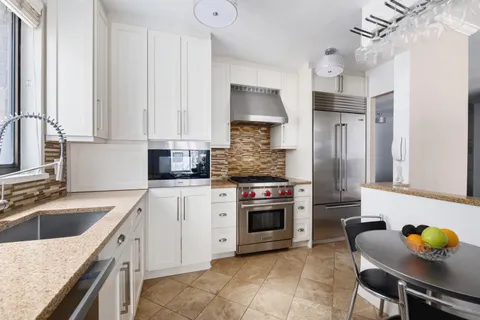 a kitchen with granite countertop a sink cabinets and stainless steel appliances