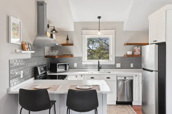 a kitchen with stainless steel appliances a table chairs and a refrigerator