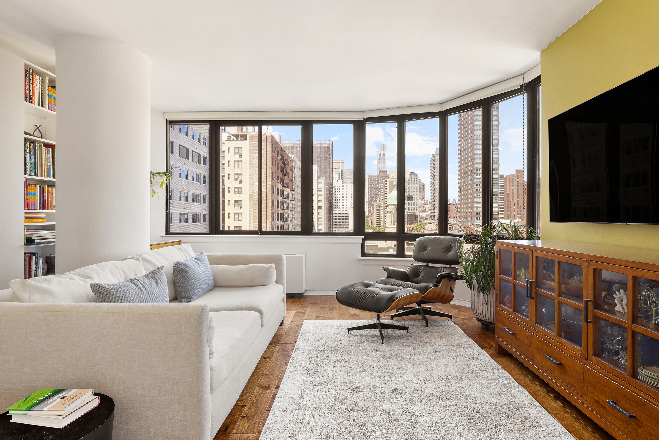 455 East 86th Street, Unit 11A Manhattan, NY 10028 - Photo 1 of 11 a living room with furniture a flat screen tv and a floor to ceiling window
