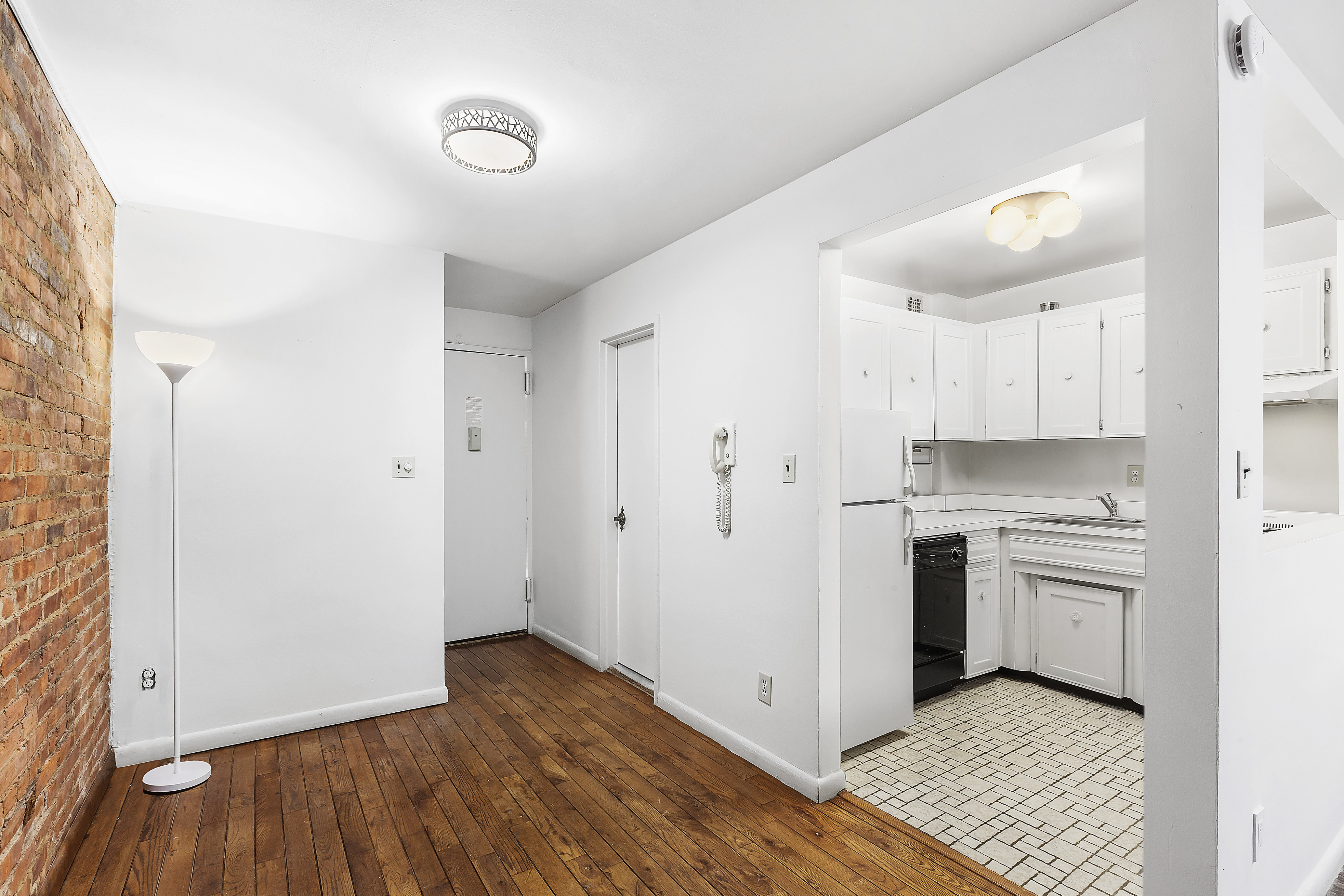 59 East 74th Street, Unit 6A Manhattan, NY 10021 - Photo 2 of 5 a kitchen with a refrigerator and white cabinets