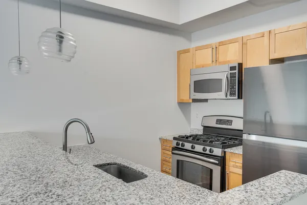 a kitchen with stainless steel appliances granite countertop a stove a sink and a microwave