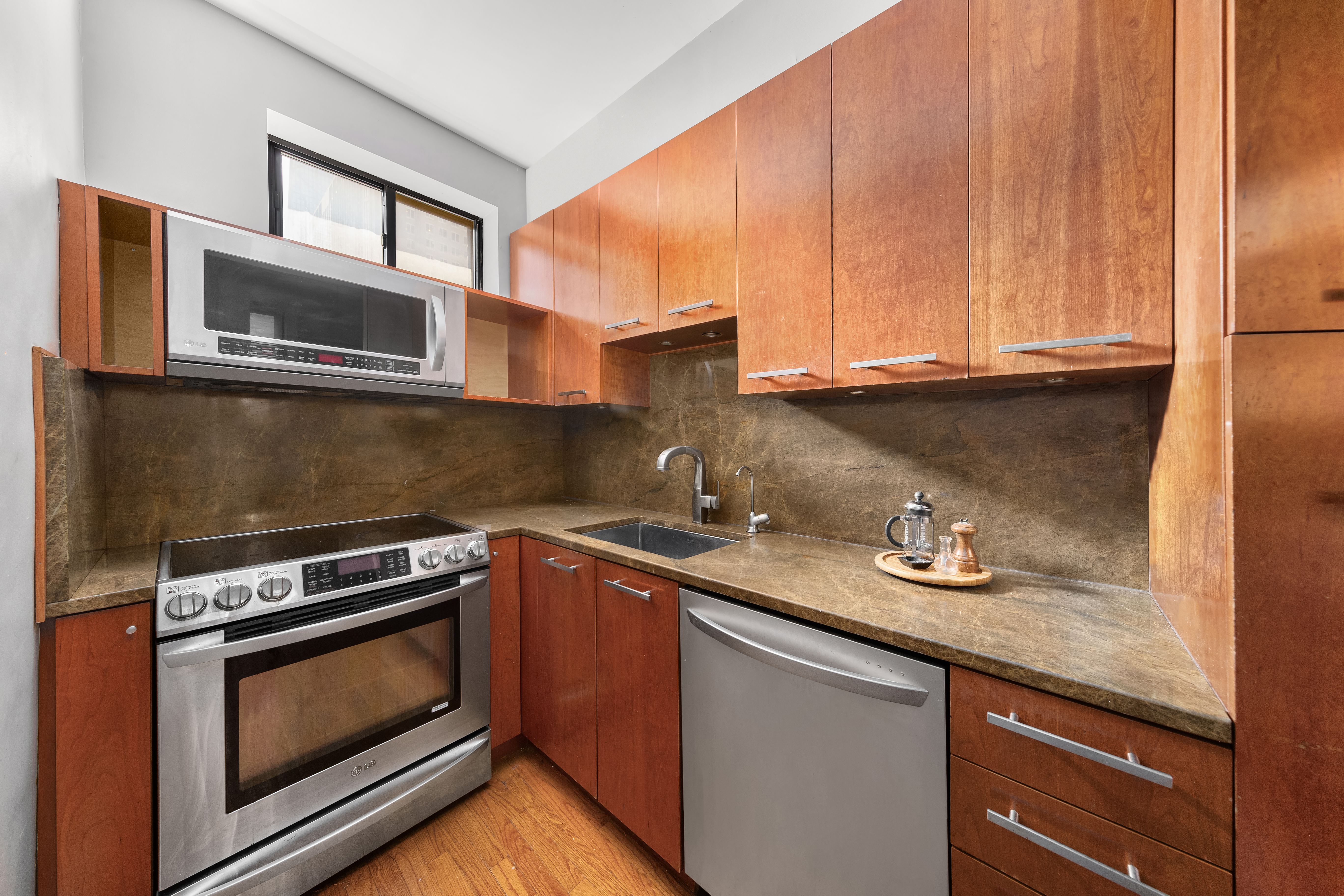 205 West 54th Street, Unit 10E Manhattan, NY 10019 - Photo 3 of 8 a kitchen with granite countertop a stove sink and microwave