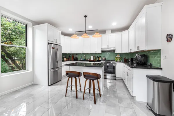 a kitchen with a refrigerator a microwave a stove and white cabinets with wooden floor