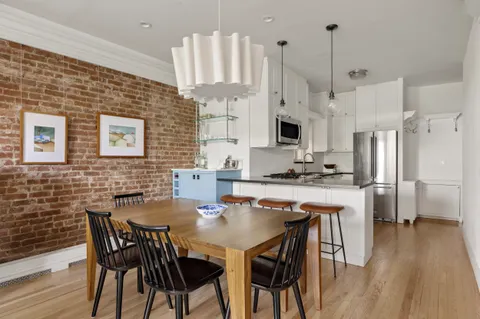 a kitchen with stainless steel appliances granite countertop a stove a kitchen island a refrigerator a stove a dining table and chairs with wooden floor