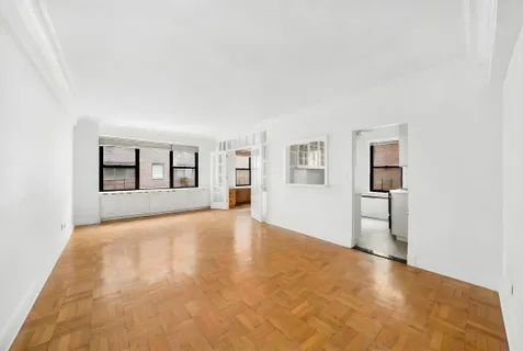a view of an empty room with window and wooden floor
