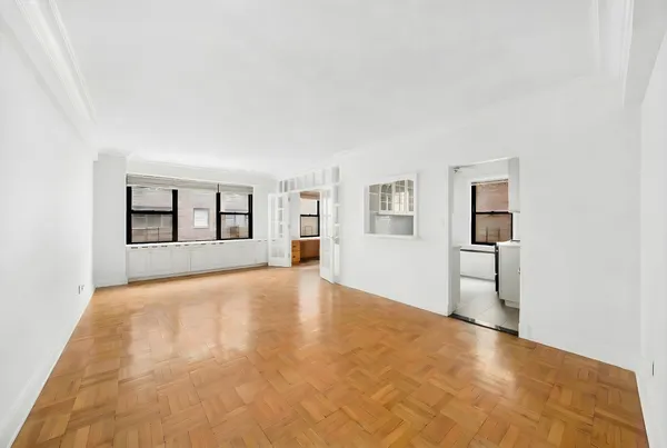 a view of an empty room with window and wooden floor