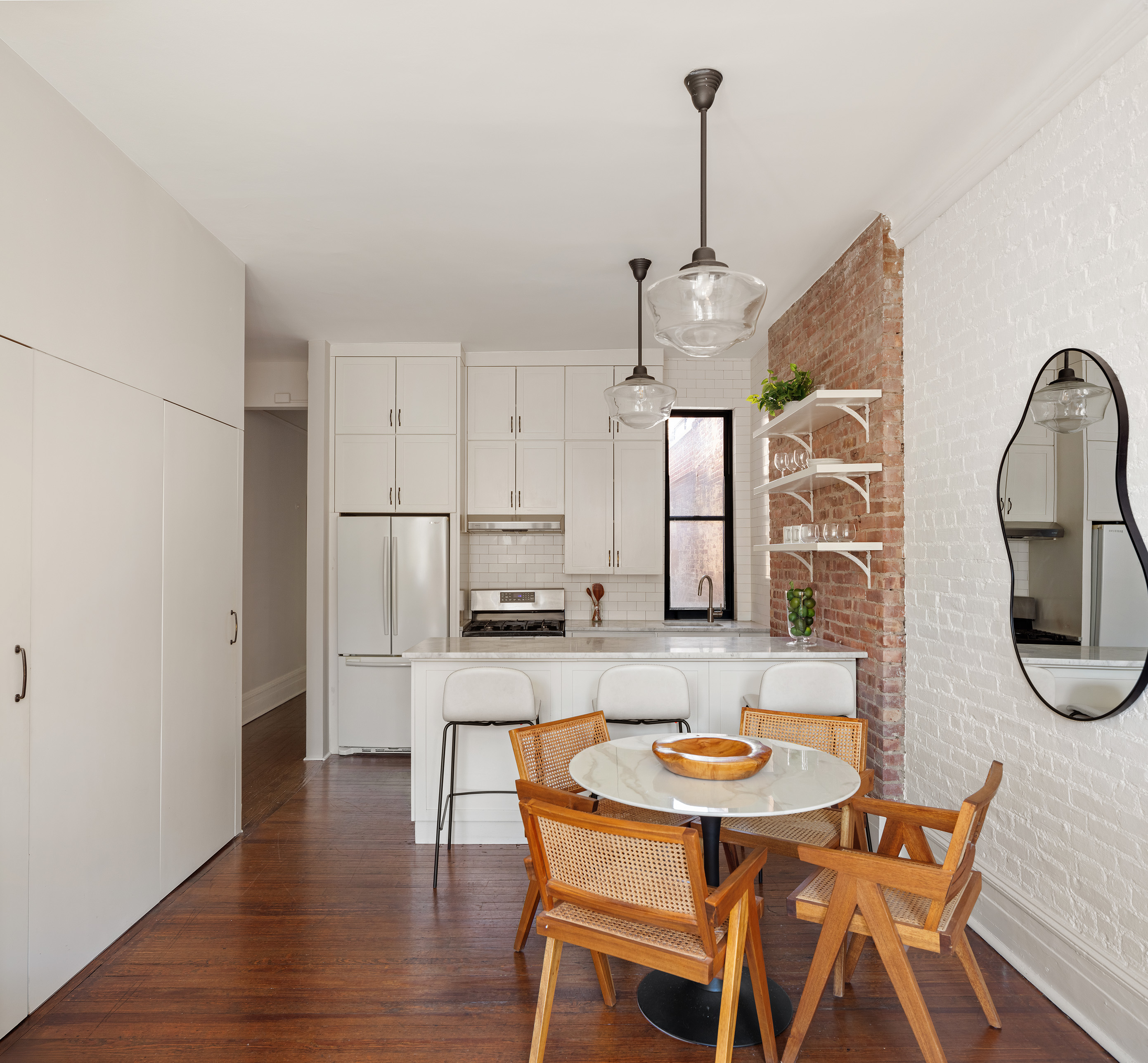 223 West 21st Street, Unit PH5M Manhattan, NY 10011 - Photo 4 of 12 a kitchen with stainless steel appliances kitchen island granite countertop a dining table chairs and white cabinets