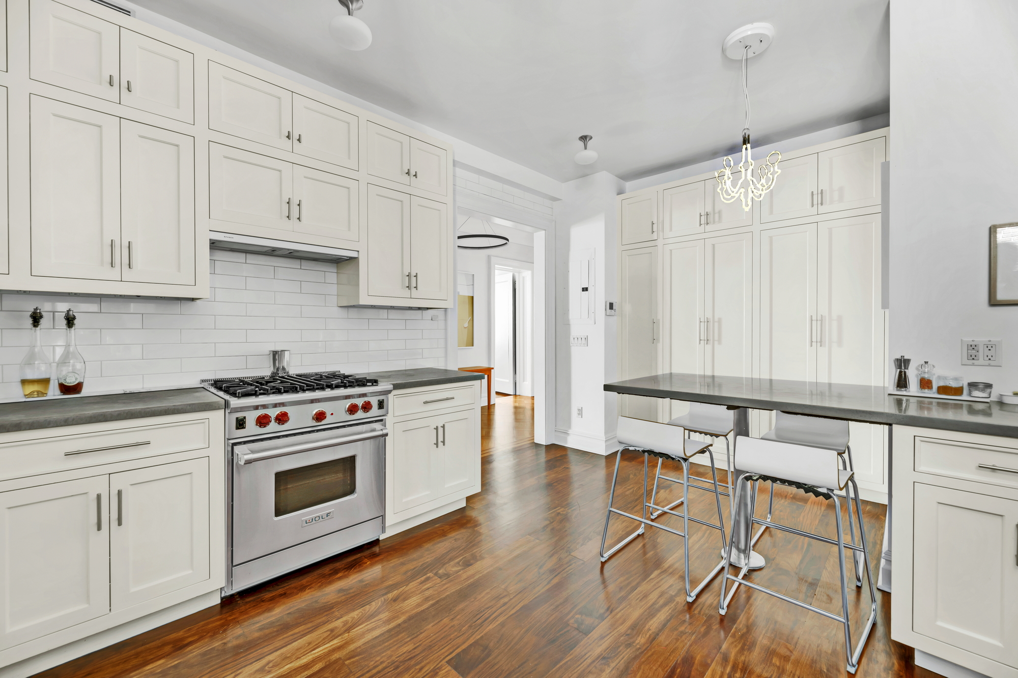 254 West 82nd Street, Unit 5A Manhattan, NY 10024 - Photo 6 of 18 a kitchen with granite countertop a stove a sink and white cabinets with wooden floor