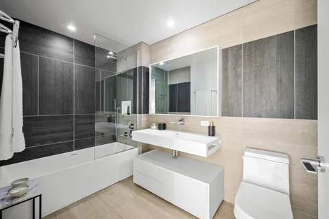 a bathroom with a double vanity sink a toilet a mirror and shower