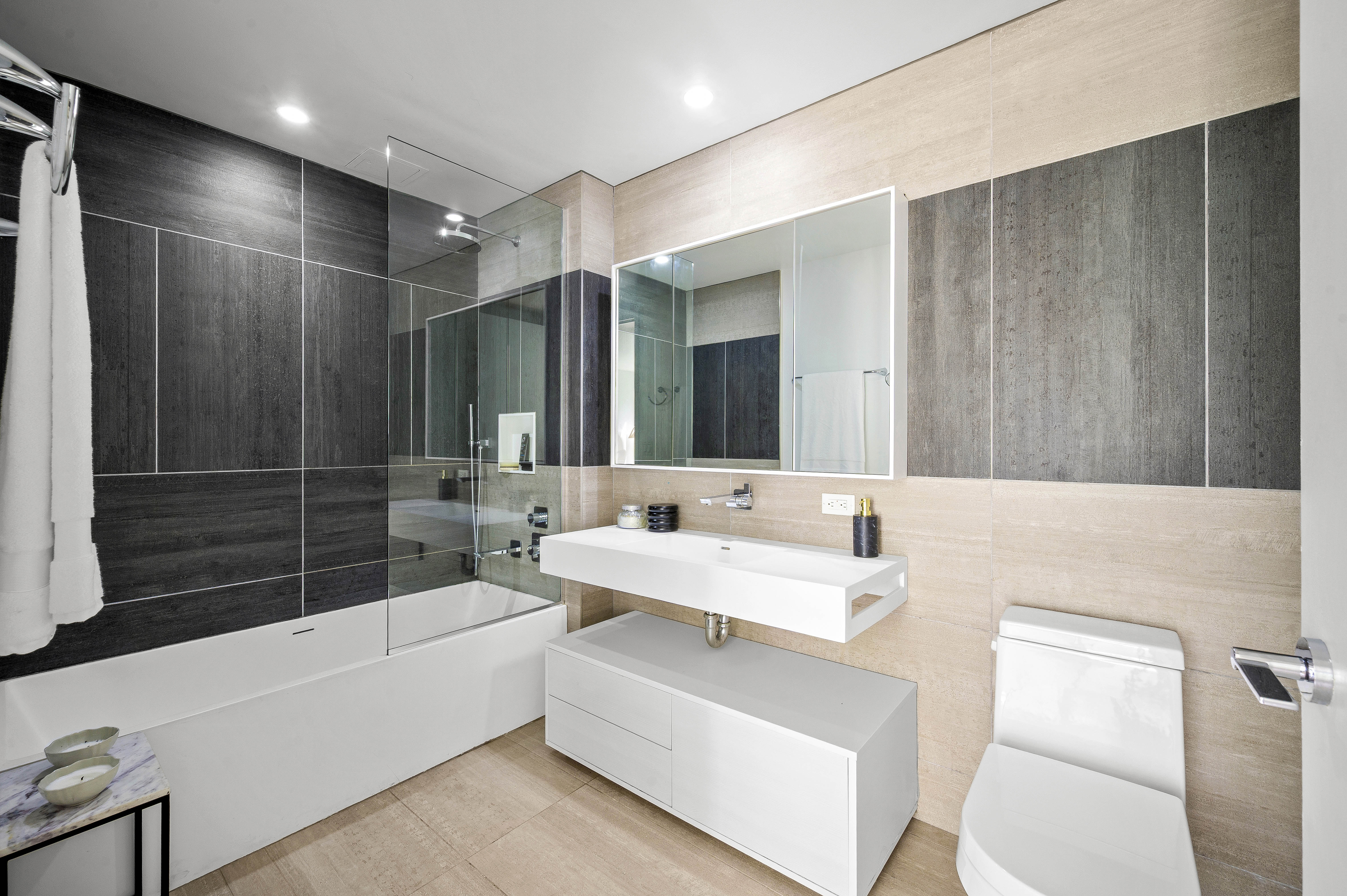 540 West 49th Street, Unit 306S Manhattan, NY 10019 - Photo 7 of 13 a bathroom with a double vanity sink a toilet a mirror and shower