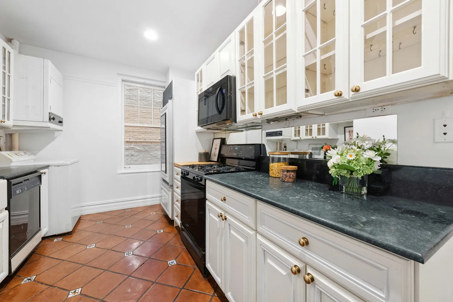 a kitchen with stainless steel appliances granite countertop a sink a counter top space cabinets and a potted plant