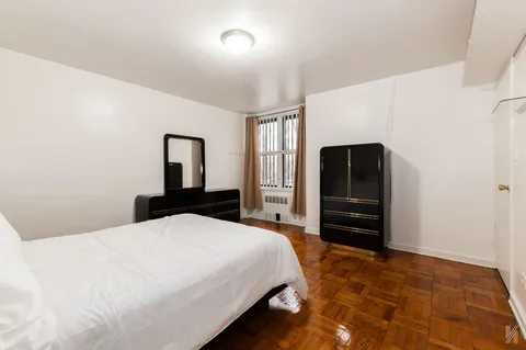 a bedroom with a bed and dresser with mirror