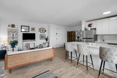 a living room with stainless steel appliances kitchen island granite countertop a sink and a flat screen tv