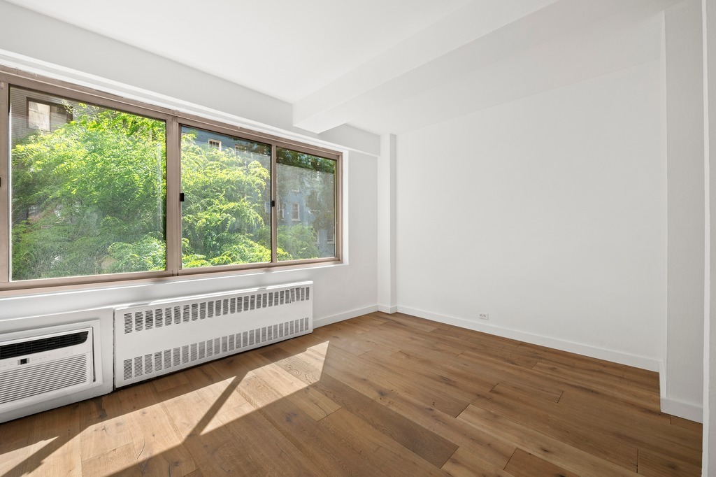 225 East 46th Street, Unit 2G Manhattan, NY 10017 - Photo 3 of 6 a view of an empty room with wooden floor and a window