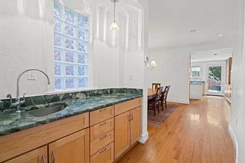 a kitchen with granite countertop white cabinets and wooden floor