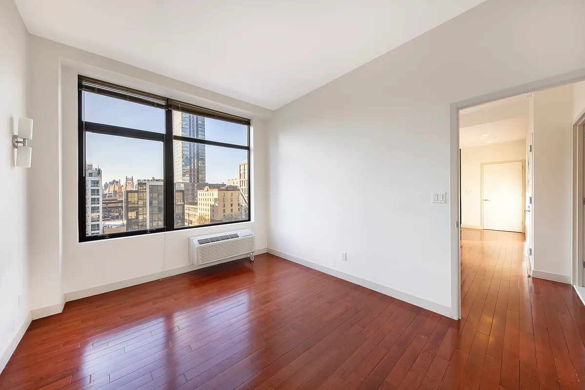51-42 27th Street, Unit 6C Queens, NY 11101 - Photo 6 of 10 a view of an empty room with wooden floor and a window